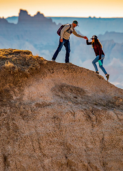 man helping a woman while hiking