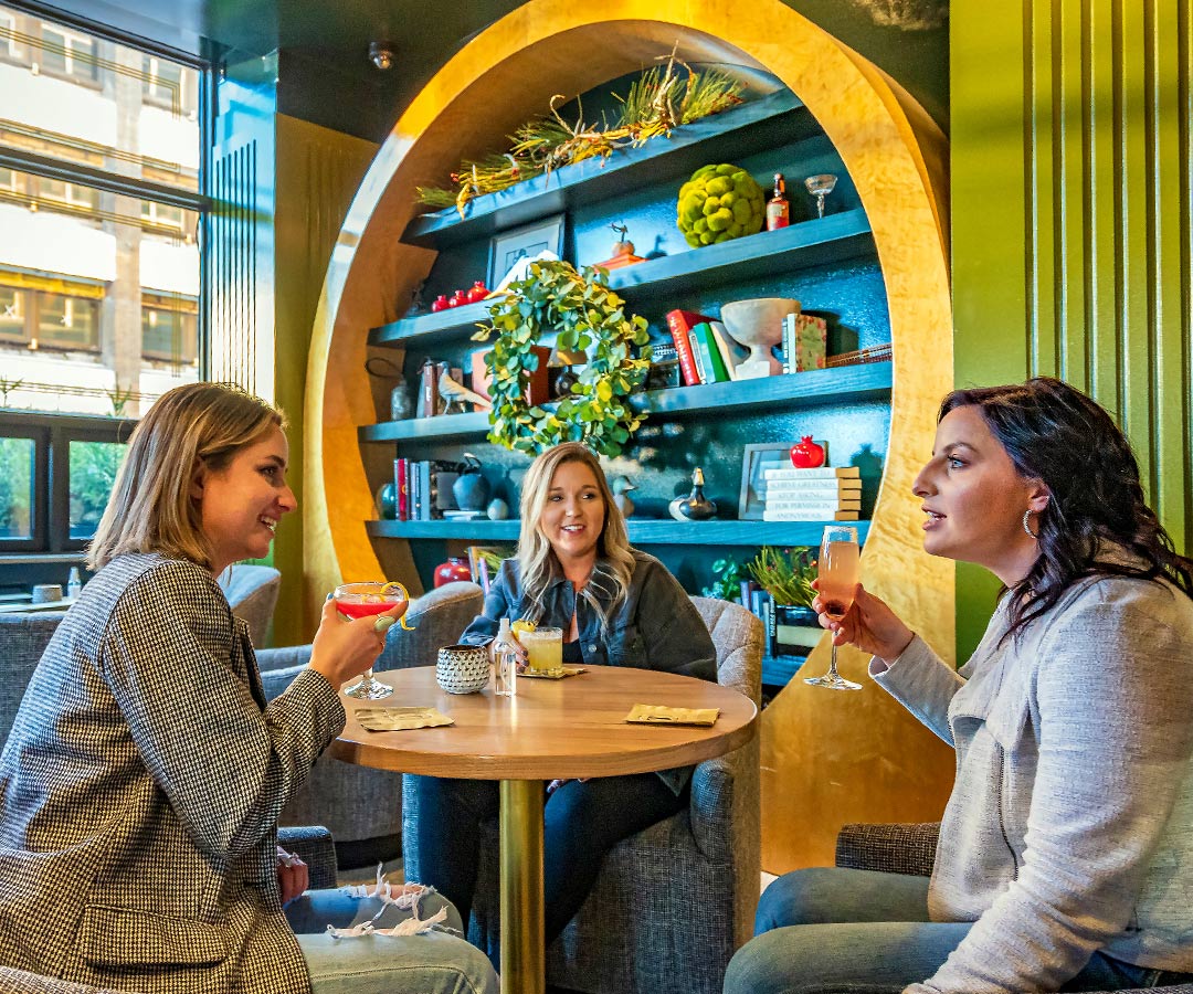 three women sitting around a table socializing